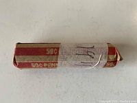 Photo of a roll of 1911 Wheat pennies wrapped in red and beige paper.