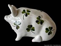 Side view of white ceramic pig figurine with green shamrocks, showcasing crackle glaze.