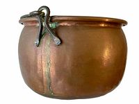 Side view of antique copper pot showing metal handle attachment and patina with oxidation streak.