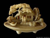 Front and angled view of detailed early plastic Japanese homestead figurine on shell base with figures, tree, boat and spinning water wheel.