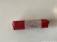 Photo of the red paper-wrapped roll of unsearched 1916 Wheat pennies with a handwritten label.