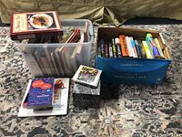 Photo showing two storage bins with various books and a boxed LED Zeppelin CD set on the floor.