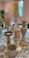 Five distressed look painted wooden candle holders with pillar candles of varying heights on a table surface