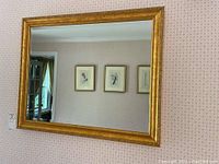 Frontal view of the large rectangular wall mirror reflecting a room with framed artwork