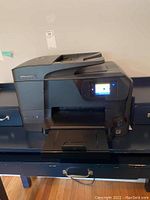 Front view of HP OfficeJet Pro 8710 printer showing touchscreen display, paper tray extended, and automatic document feeder on top.