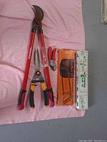 All tools laid out including the boxed Wyoming collapsible saw, Great Neck hacksaw, Corona loppers, hand pruners and shears on a pink cloth background.