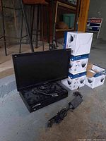 Overall lot showing monitor atop NVR hub and four camera boxes stacked to right