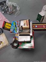 Photo showing a stack of various board games, poker chips in containers, bicycle lock, and speed ball toy.