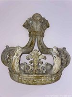 Front view of a crown-shaped wall hanging relief with detailed scroll and floral designs in a weathered finish