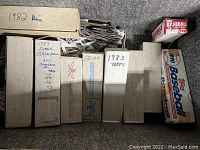 Open trunk showing multiple white storage boxes labeled with years and brands, loose cards peeking out