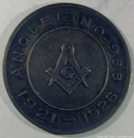 Front of round 1.18 inch sterling silver Masonic medal with compasses and square symbol and text 'ANGLE - NO. 988 1921-1926' around the edge.