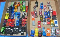 Top-down image of assorted Hot Wheels diecast cars in a box, showing a variety of colors and models including limousines arranged in rows.