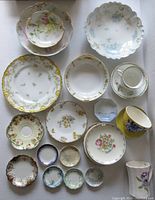 Top view of 21 pieces including floral decorated plates, butter pats, and small cups in various colors and trims
