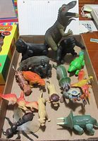 Box of assorted dinosaur and animal toys including gorillas and Lion King characters