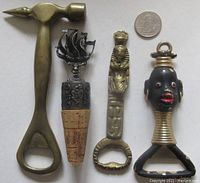 Full view of the four decorative brass bar tools including hammer opener, ship cork topper, Egyptian style opener, and native style opener with red jewel eyes.