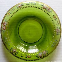 Top view of shallow green glass candy bowl showing circular shape and hand-painted enamel roses and dot pattern around rim.