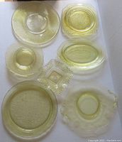 Top view of seven pieces of yellow glass plates and dishes with various patterns and shapes