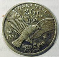 Close-up photo of the front side of the silver token showing the eagle design, markings including 2 Gr Fine Silver .999, year 1776, and serial number 852878.