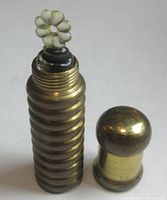 Photo showing brass screw top container with ribbing detail and dome-shaped cap