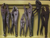 Close-up of six various locking and slip joint pliers with adjustment screws and serrated jaws on a yellow tray.
