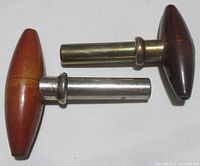 Two vintage cork extractors placed side by side showing wood handles and metal tine covers.