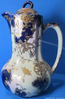 Victorian pastel tinted chocolate pot showing front angle with handle and ornate gold and cobalt blue enamel decoration.