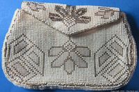 Front view of vintage beaded hand purse showing detailed beadwork with geometric and floral patterns in white and beige colors.