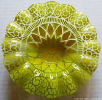 Top view showing sunflower design and scalloped edges of yellow glass candy bowl.