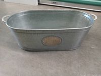 Side view of the galvanized aluminum tub showing the oval 'Cheers' plaque and one handle.