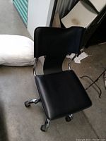 Black leather seat and backrest of office chair showing overall shape and material condition.