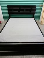 Assembled queen-size bed frame with headboard, side rails, and covered support board installed