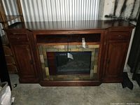 Full front view of wood cabinet with faux fireplace heater insert showing mantle centerpiece and full cabinet structure