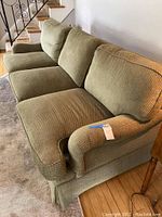 Side angle view of the green fiber foam sofa showing textured upholstery, three seat and back cushions, and rounded armrest.
