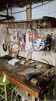Full view of workbench and pegboard showing assorted tools, jars with hardware, cords, and packaged items.