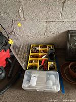 Plastic tool box with yellow segmented compartments filled with various hardware including screws, nuts, bolts, and electrical connectors.