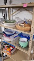 Wide shot of metal shelving with stacked plates, bowls, storage containers, and baskets.