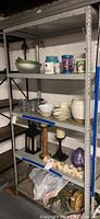 Full view of metal shelving unit with some household items on shelves, shows four shelves and the overall condition of the shelf.