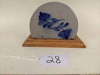 Front view of ceramic napkin holder showing blue floral pattern on gray stoneware set in wooden base.