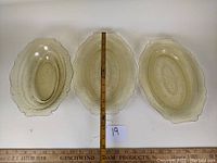 Three pieces of amber Depression glass Patrician pattern laid flat with ruler for size context showing two platters and one vegetable bowl.