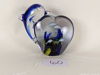 Front view of art glass paperweight showing clear heart-shaped aquarium with blue and yellow interior details and attached blue porpoise figurine.