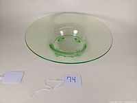 Top-down view of a wide green uranium glass fruit bowl showing the smooth flared rim and central base.