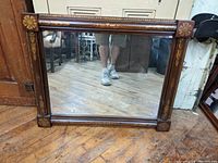 Full view of the large rectangular wall mirror with wooden frame and floral/leaf stenciled decoration.