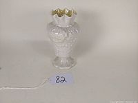 Front and side view of the 7-inch white Belleek porcelain vase showing raised floral and scroll patterns and ruffled top