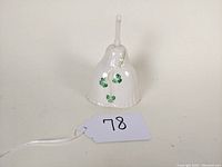 Front view of porcelain bell showing shamrocks on the surface and handle design.