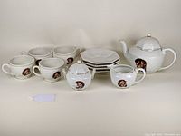 Full tea set arranged including teapot, creamer, sugar bowl, 6 cups, and 6 saucers with Hummel Umbrella Boy and Girl prints