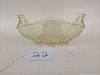 Front angled view of square etched glass bowl showing embossed floral or geometric patterns and slight yellow tint.