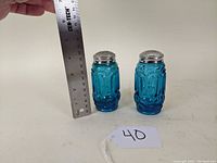 Pair of blue Moon & Stars pattern salt and pepper shakers with metal lids and ruler showing height