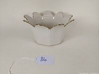 Front angled view showing the flared, scalloped rim with gold trim, ribbed vertical texture on the body of the bowl, and overall shape.