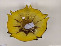 Top view of yellow mid-century art glass bowl showing petal-like ruffled edges and central inner molding.