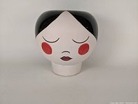 Front view showing face with closed eyes, red cheeks, and lips.